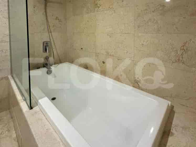 A bathroom with a bathtub, tiled walls, and a glass shower screen.