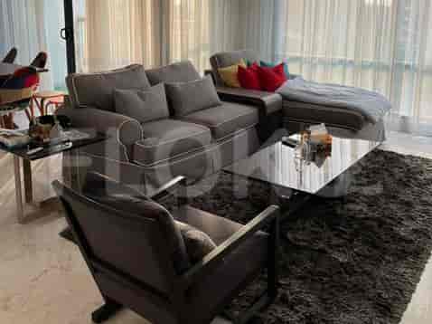 A modern living room featuring a comfortable L-shaped grey sofa, a glass coffee table, and a plush dark rug.