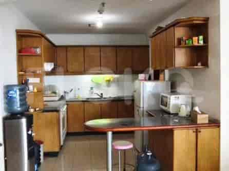 A kitchen with wooden cabinets, a countertop, a refrigerator, a microwave, and a water dispenser.