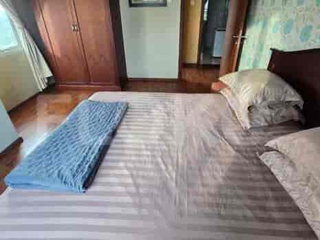 A bedroom with a queen-sized bed, wooden wardrobe, and a window with a city view.