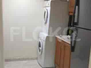 A laundry area with stacked white washing machine and dryer, and a refrigerator.