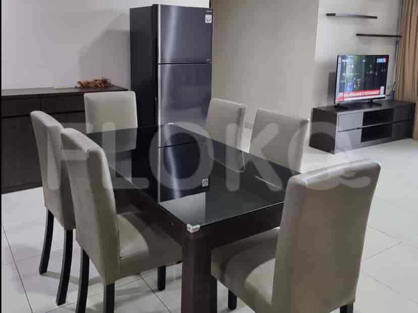 A dining room featuring a dark wood dining table with a glass top, surrounded by six upholstered chairs, and a large black refrigerator.