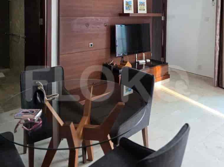 A living room area featuring a wall-mounted TV, wooden paneling, and a glass-top dining table with chairs.