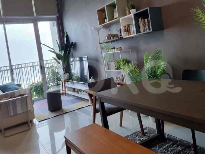 A contemporary living and dining area with a dark wood dining table, a comfortable sofa, a large TV, and expansive windows offering a scenic view.