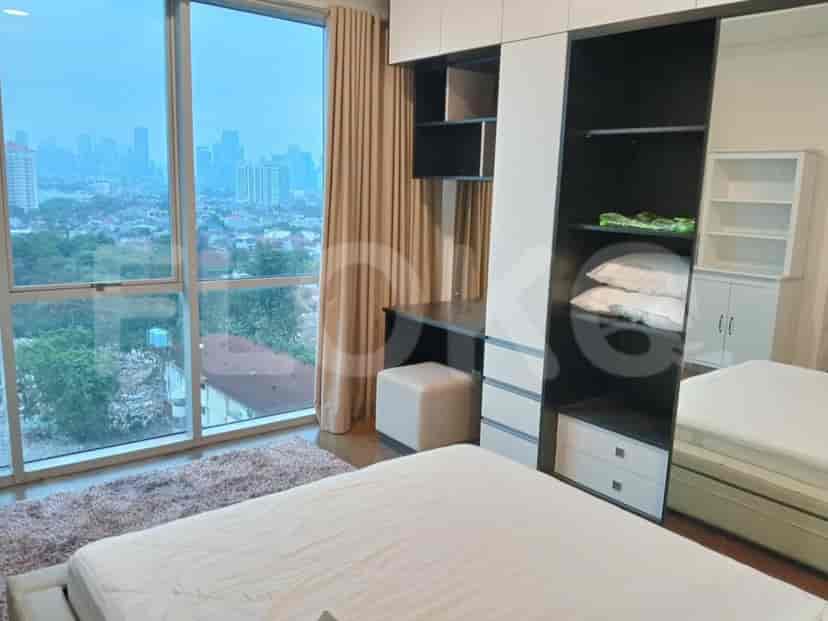 A bedroom with a large window offering a city view, a bed, a dresser, and a large built-in wardrobe.
