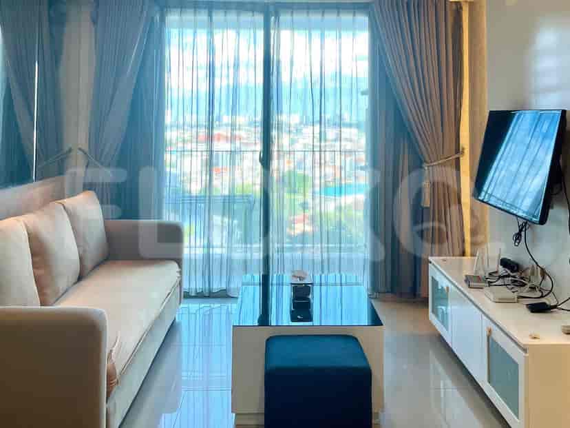 Modern living room with a sofa, coffee table, and a TV, with a city view.