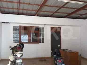 Tampilan interior garasi atau area penyimpanan dengan sepeda motor dan lemari kayu.