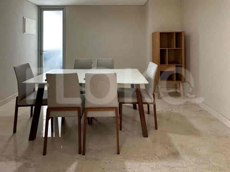 A dining room featuring a white rectangular table with six chairs and a wooden shelving unit.