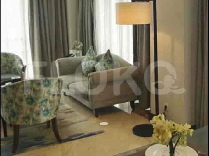 A living room featuring a loveseat with decorative cushions, a patterned armchair, and a floor lamp.