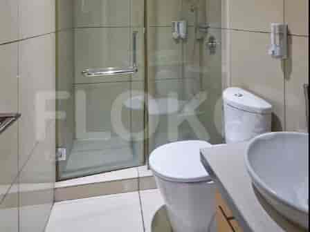 Kamar mandi modern dengan pancuran berkaca, toilet, dan wastafel.