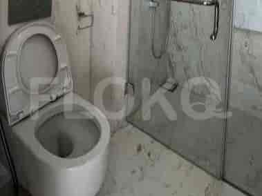 A modern bathroom with a toilet, glass shower enclosure, and marble walls.