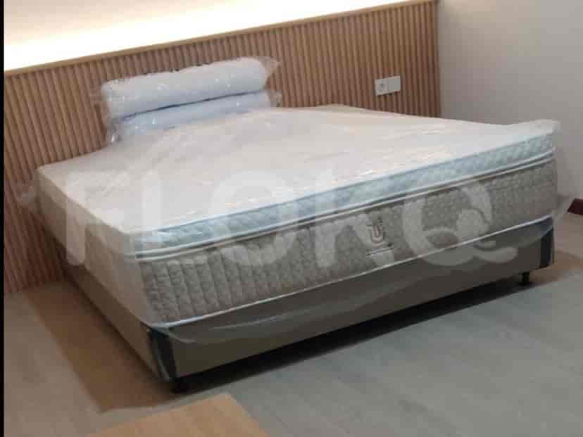 A bedroom featuring a bed with a wooden headboard, covered in plastic wrap.