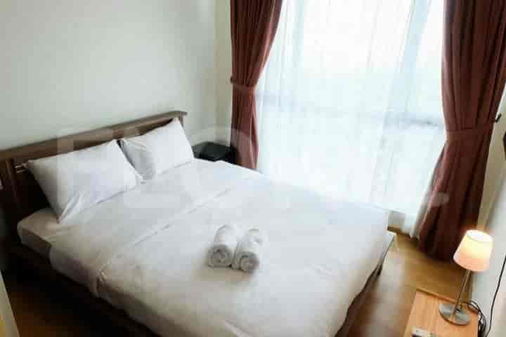 Bedroom featuring a bed with white bedding and large windows with brown curtains.