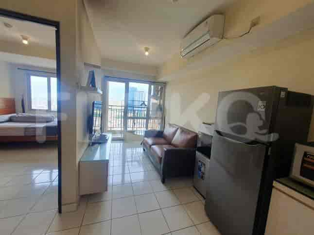 A living room with a sofa, refrigerator, and access to the kitchen and bedroom.