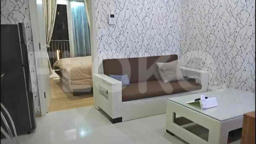 Ruang tamu dengan sofa, meja kopi, dan pemandangan ke kamar tidur.