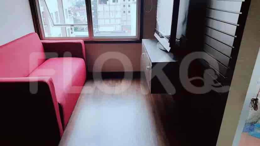 Bright living room with a red sofa, television, and a view of the city.