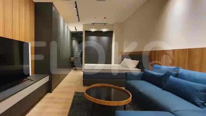 A modern studio apartment living space with a bed, sofa, and TV.