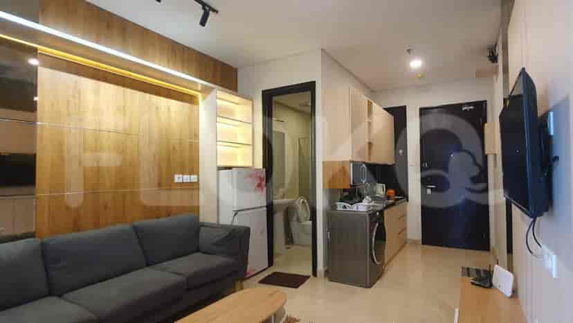 Modern apartment with combined living and kitchen area. Features grey sofa, wood paneling, and a modern kitchen setup.