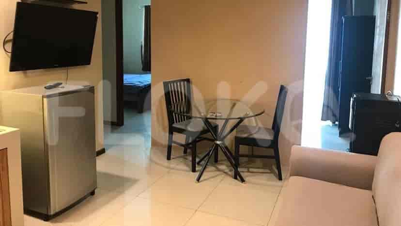 Living area with a TV, mini-fridge, and dining set.