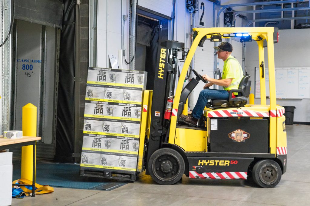 man with yellow forklift moving boxes