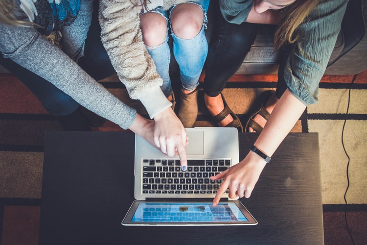 three people pointing out to computers