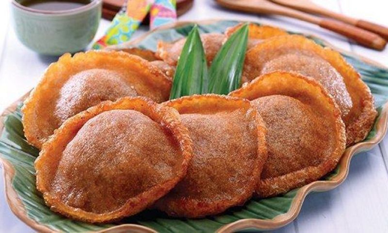 Kue cucur served on banana leaves with pandan leaves as garnish